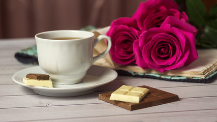 Fototapeta na wymiar Romantic St Valentine's setting with chocolate, tea cup and red roses