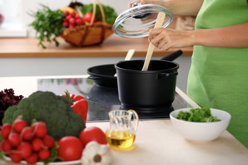 Young woman is cooking by the stove in the kitchen, close up.