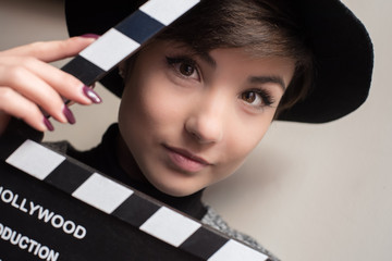 Portrait of young actress holding a movie clapper