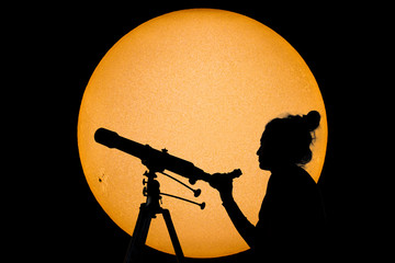 Silhouette of a woman with telescope Safe Sun observation