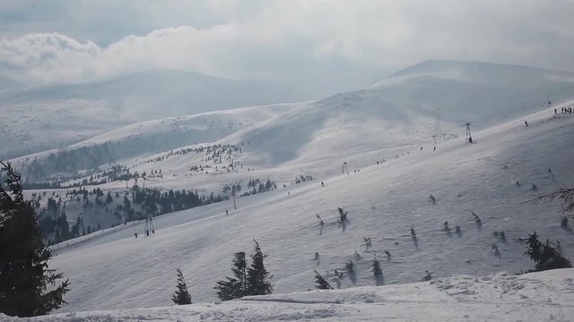 ski resort on windy day; people are skiing despite strong blizzard