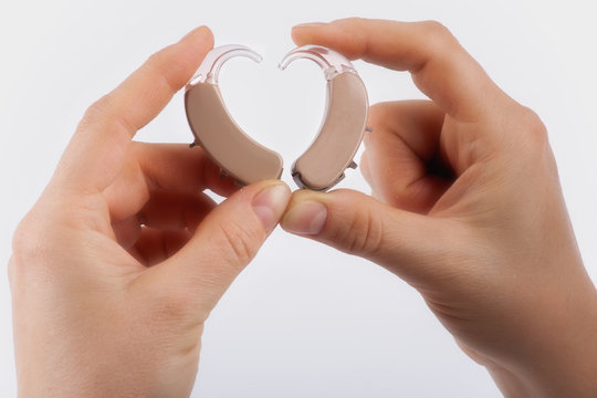 Hands forming a heart shape from hearing aids