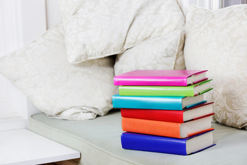 Window seat with cushions and a pile of books in a reading corner