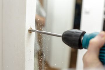Man drilling a hole in a wooden the door in a room