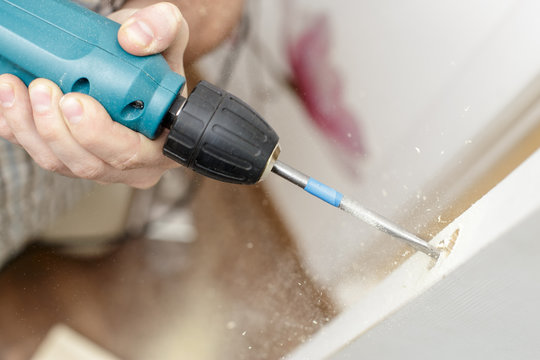 Man drilling a hole in a wooden the door in a room