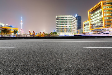 Asphalt road and modern cityscape at night in Shanghai