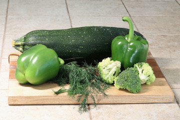 Vegetables on a stone kitchen countertop. Assorted green vegetables for healthy eating. Food ingredients ready for cooking. Horizontal composition.