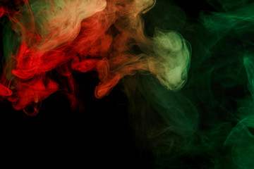 Fototapeta premium Abstract smoke Weipa. Personal vaporizers fragrant steam. The concept of alternative non-nicotine smoking. Red green smoke on a black background. E-cigarette. Evaporator. Taking Close-up. Vaping.