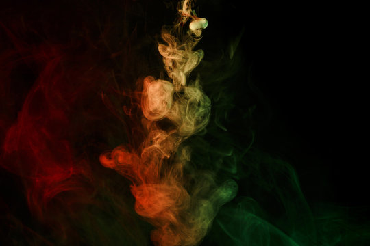 Abstract smoke Weipa. Personal vaporizers fragrant steam. The concept of alternative non-nicotine smoking. Red green smoke on a black background. E-cigarette. Evaporator. Taking Close-up. Vaping.