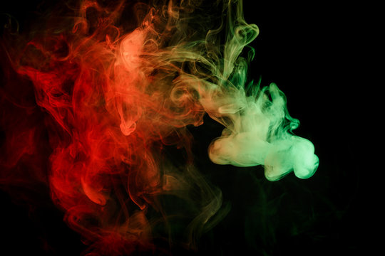 Abstract smoke Weipa. Personal vaporizers fragrant steam. The concept of alternative non-nicotine smoking. Red green smoke on a black background. E-cigarette. Evaporator. Taking Close-up. Vaping.