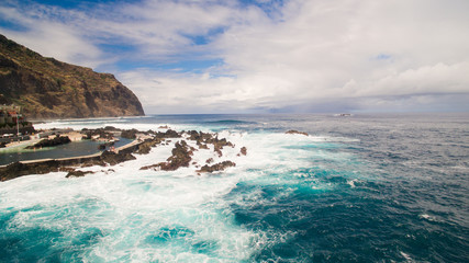 Waves and rocks near city pools of Porto Moniz aerial view