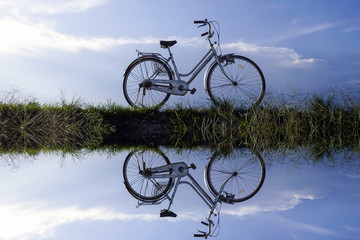 Reflection of Old vintage bicycle with dramatic blue sky at background