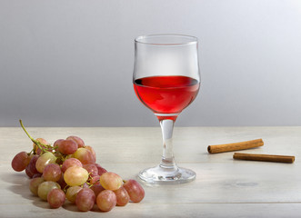 Натуральное виноградное вино.\Бокал  виноградного красного  вина, гроздь винограда и корица.