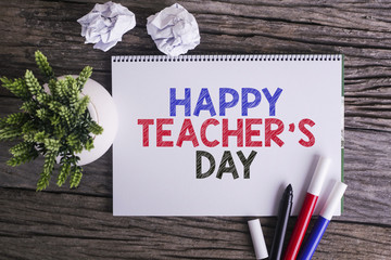 Notepad and green plant on wooden background with HAPPY TEACHER'S DAY