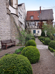 Old courtyard of Waiblingen with leafy green bushes trimmed in the form of balls. Half-timbered house in perspective. Vertical view. Germany. 