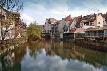 Naklejka na ściany i meble Old buildings, arch bridge and tree reflected in water. Nuremberg, Bayern, Germany