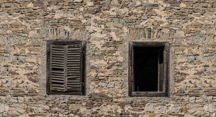 Old building in Northern Italy broken down and worn with windows and old stone facade