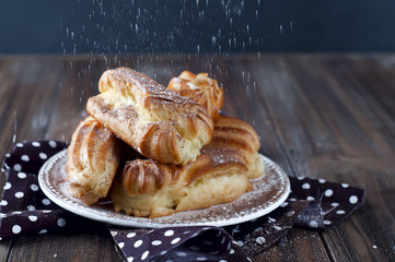 Tasty eclairs on wooden table