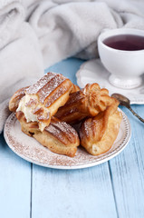 Tasty eclairs on wooden table
