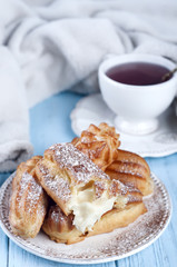 Tasty eclairs on wooden table