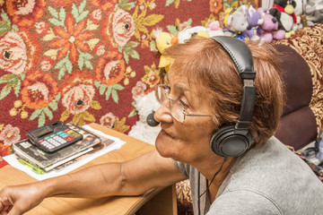 elderly woman with headphones at a computer 
