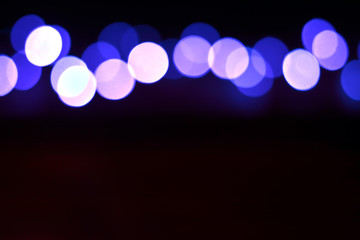 Multicolor lights out of focus. New Year bokeh postcard. Blurred illumination on the black background. Place for design and text