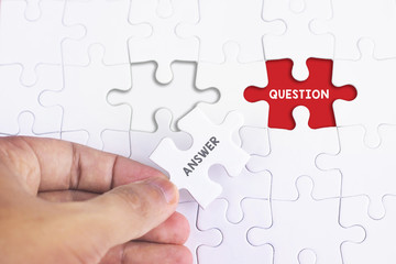 Fototapeta premium Business Concept - Female hand and missing puzzle with ANSWER and QUESTION word