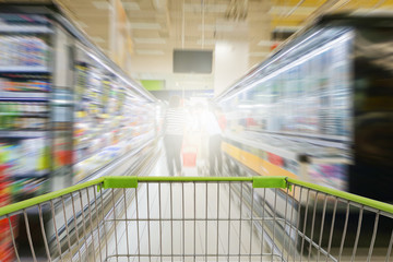 Fototapeta premium Supermarket aisle with empty green shopping cart