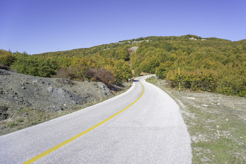 Ascend highway turn against Indian summer foliage on Mountain Pelion slope background. Greece. 
