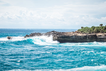 A beautiful blue wave crashes down at the rocks in Devil's Tear, tropical island Nusa Lembongan, Indonesia, Asia. Sunny day, big waves.