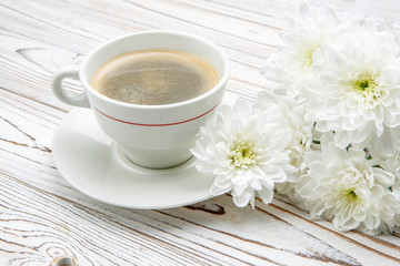 cup of coffee and flowers on light wooden table