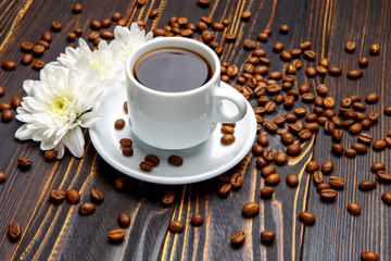 cup of coffee and flowers on dark wooden table