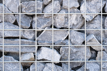 Steel mesh of gabion wall.Grey stones in gabion