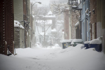 Gusts of wind blow clouds of snow in an alley in Washington DC