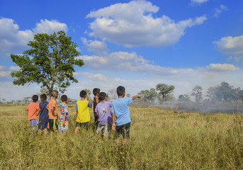 Many children were gathering around a fire burning.