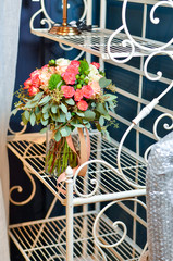 Букет из роз в прозрачной стеклянной вазе стоит на ажурной подставке