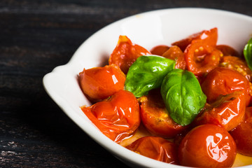 Tomatoes and basil leaves with olive oil on old wooden table. Shallow depth of field.