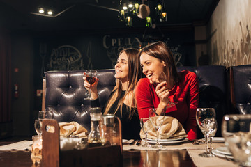 Two beautiful happy women having fun in a bar drinking wine