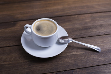 From above shot of cup with tasty coffee standing on wooden table .