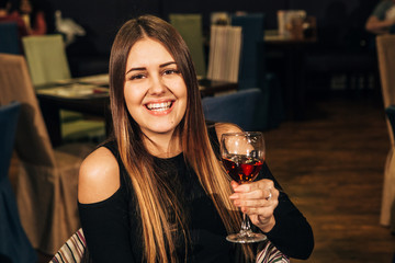 beautiful young woman tasting wine in a restaurant and smiling
