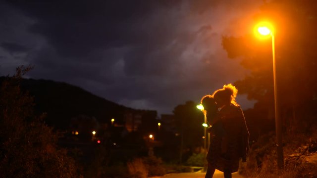 Mother and child kiss on an evening walk on the promenade. Happy family having fun before bedtime. Mom and son enjoy the evening