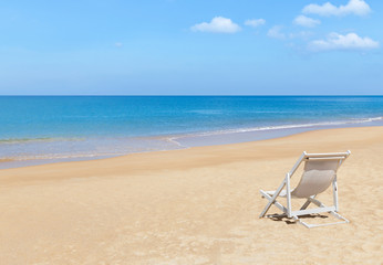 Empty white wooden beach chair on tropical beach with  blue sky background