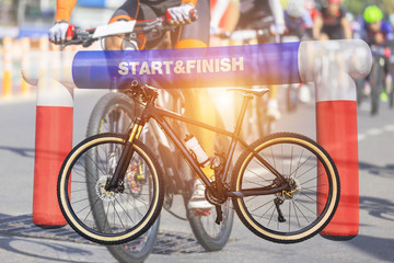 Double exposure mountain bicycle and inflatable start - finish arch with cyclists during bicycle...