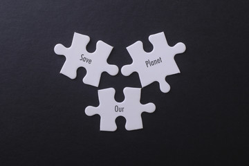 White puzzle on black background with Save Our Planet Word.