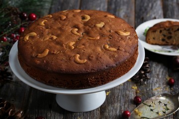 Homemade dark Christmas fruit cake on rustic wooden background, selective focus