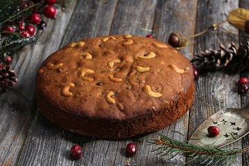 Homemade dark Christmas fruit cake on rustic wooden background, selective focus