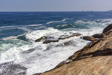 Fototapeta na wymiar Waves crashing against rocks in the afternoon