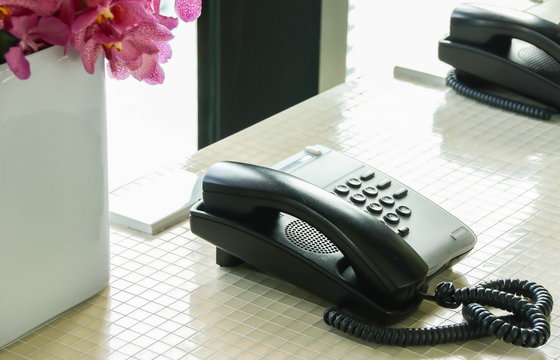 Black landline telephone on counter desk in the hotel.
