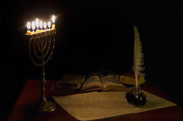 Old writing desk iluminated by menorah. Text in the notebook is in old Bulgarian ecclesiastical...