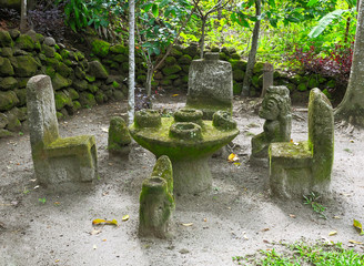 Ancient Indonesian sculptures of backchairs and table carved from stone, at Ambarita Stone Chairs worship, Lake Toba, Samosir, Indonesia